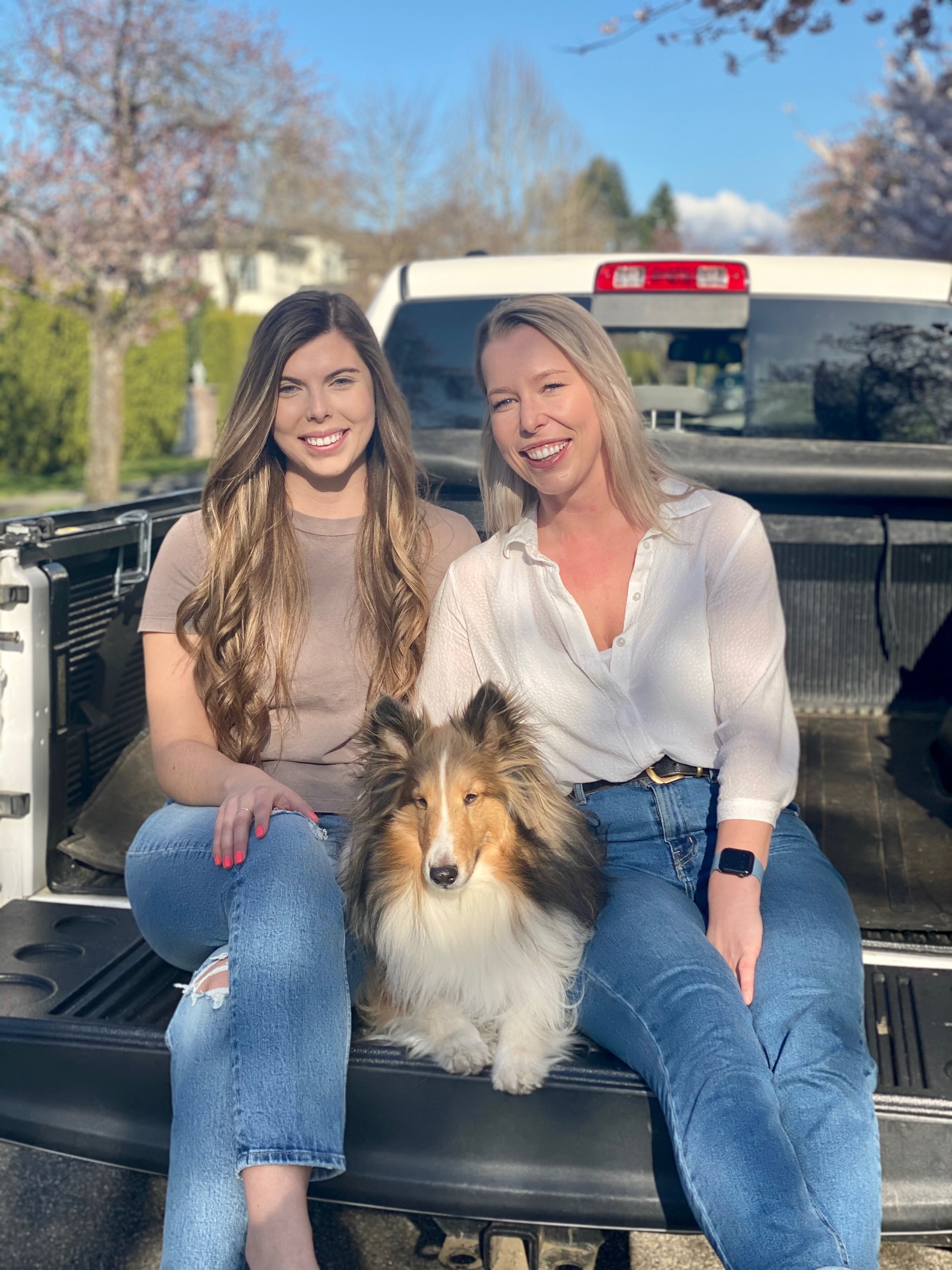 Madison McDougall and Alexsandra Dann sitting on a truck tailgate with their sheltie